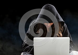 Woman hacker working on laptop in front of black background