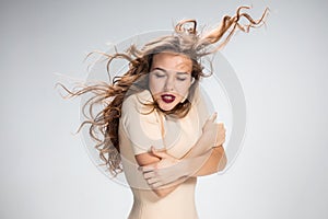 The woman with hair blowing in the wind on gray