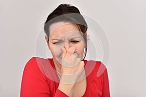 Woman with hair bun holding her nose