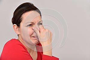 Woman with hair bun holding her nose