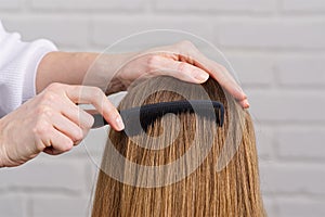 Woman hair care. Hairdresser making hairstyle to young girl in beauty salon.