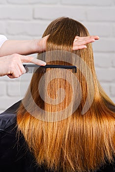 Woman hair care. Hairdresser making hairstyle to young girl in beauty salon.