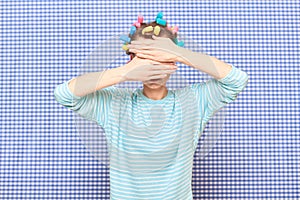 Woman with hair curlers on head is covering her face with hands