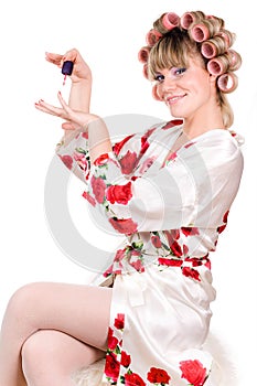 Woman with hair curlers manicuring photo