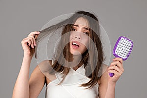 Woman with hair loss problem. Portrait of Young girl with a bald. Head shot of a nervous girl with a hairbrush.