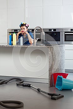 Woman with hair rollers sitting bored in a beautiful kitchen