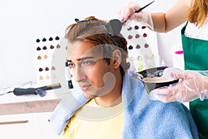 The woman hairdresser applying dye to man hair