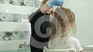 Woman hairdresser colorist at home in the bathroom puts paint on the hair of a young woman, applies paint with a brush