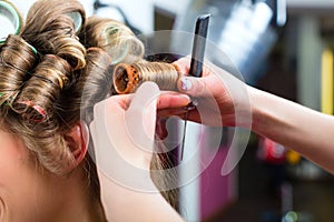 Woman at the hairdresser curling hair