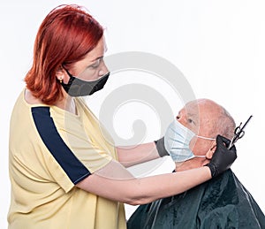Woman hairdresser cutting hair to a senior man in face mask