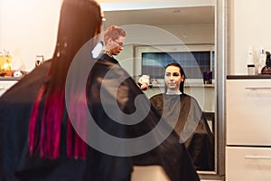 Woman hairdresser drying young woman customer hair in salon