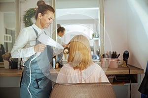 woman hairdresser in hair studio blowout hair with hair dryer