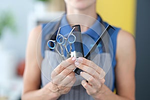 Woman hairdresser holding hair scissors and comb in hands closeup