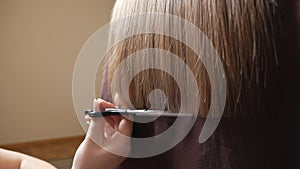 The woman hairdresser holds fingers, a comb and scissors in a hand between hair. Cut the ends of the hair with scissors