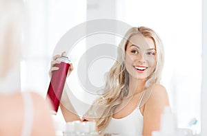 Woman with hairspray styling her hair at bathroom photo