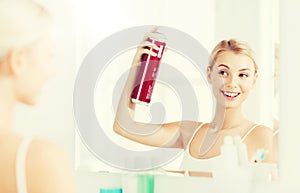 Woman with hairspray styling her hair at bathroom