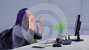 A woman with half of her face in a mask of green clay on a blue background