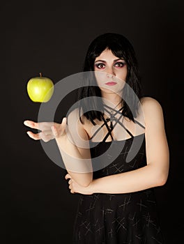 Woman with halloween make up sthrowing green apple