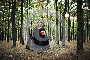 Woman in halloween witch costume in forest