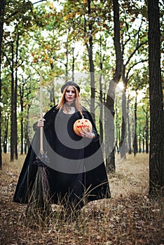 Woman in halloween witch costume in forest