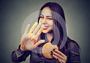 Woman with hamburger rejecting advise on healthy eating