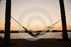 Woman in hammock enjoying sunset on the beach. Vacation concept.