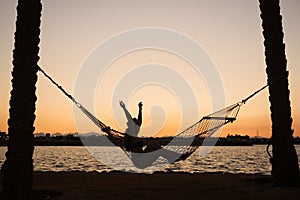 Woman in hammock enjoying sunset on the beach. Vacation concept.