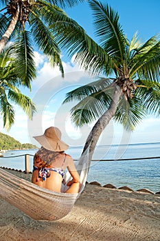 Woman on hammock in tropical island palm trees