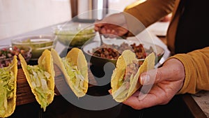 Woman hand adding the ground meat and vegetables filling to a taco