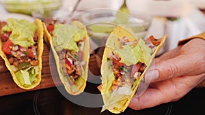 Woman hand adding the guacamole topping to tacos