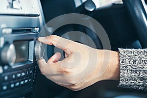 Woman hand adjusting the sound volume of car radio