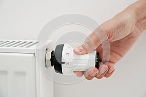 Woman hand adjusting temperature on heat radiator