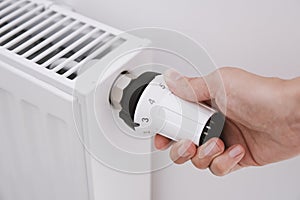 Woman hand adjusting temperature on heat radiator