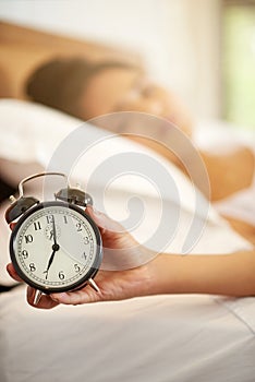 Woman, hand and alarm with zoom, sleeping and tired or lazy in morning with snooze and person in house. Bedroom, watch photo