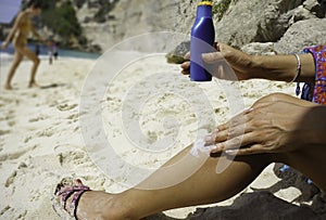 woman Hand applying sunscreen creme on Leg. Skincare. Sun protection on the beach