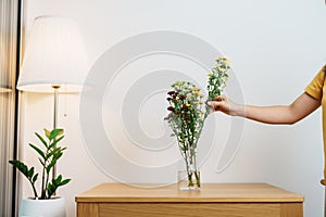 Woman hand arrange Colorful flowers bouquet in mason jar on table background. Happy day with fresh flower