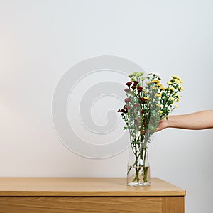 Woman hand arrange Colorful flowers bouquet in mason jar on table background. Happy day with fresh flower