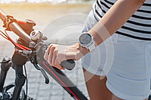 Woman. hand on bicycle handlebar, white smart watch on wrist