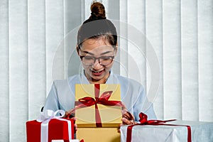 Woman hand in a blue shirt opening a gold gift box tied with a red ribbon present for the festival of giving special holidays like