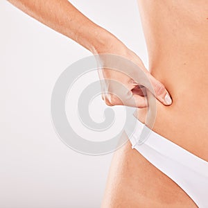 Woman hand, body weight and loss for liposuction, tummy tuck and abdomen in underwear in grey studio background
