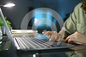 Woman hand browsing on laptop using touchpad in the night