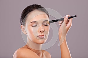 Woman, hand and brush for eye makeup in studio, skin for eyeshadow and beauty with application on grey background