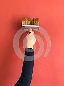 Woman hand with a brush paint the wall grenadine