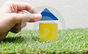 Woman hand building a small house with colorful wooden blocks