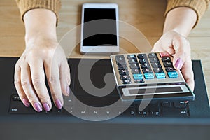 Woman hand calculating and making online payment with computer laptop and smart phone