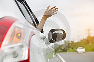 Woman hand at the car window on an empty country road.