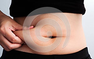 Woman hand catching fat body belly paunch , diabetic risk factor