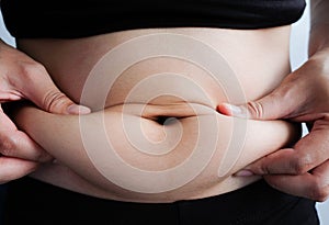 Woman hand catching fat body belly paunch , diabetic risk factor