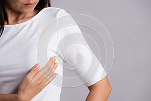 Woman hand checking lumps on her breast for signs of breast cancer on gray background. Healthcare concept