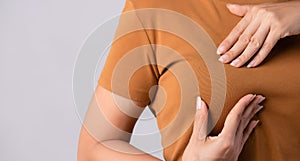 Woman hand checking lumps on her breast for signs of breast cancer on gray background. Healthcare concept